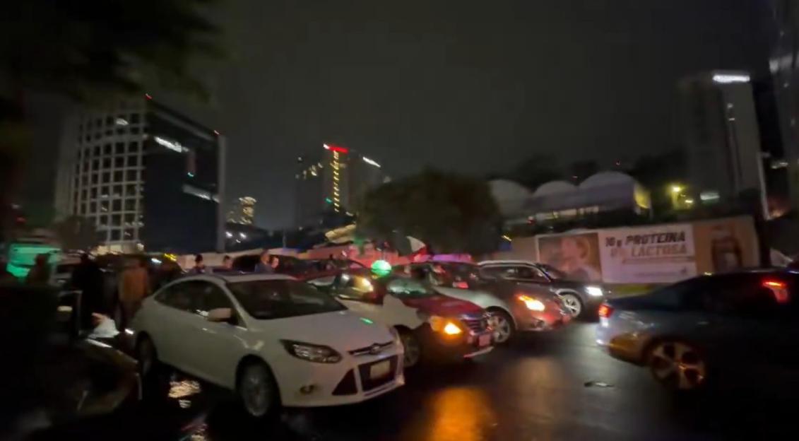 Traffic jam at night with cars stalled on a wet street.