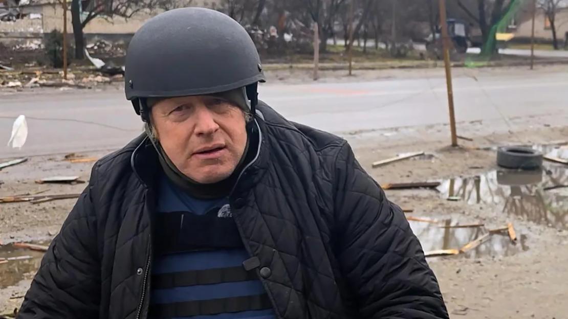Boris Johnson wearing a helmet and a flak jacket on the front line with Ukrainian soldiers.
