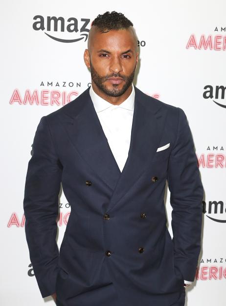 Ricky Whittle wearing a dark blue suit with a white shirt and white pocket square.