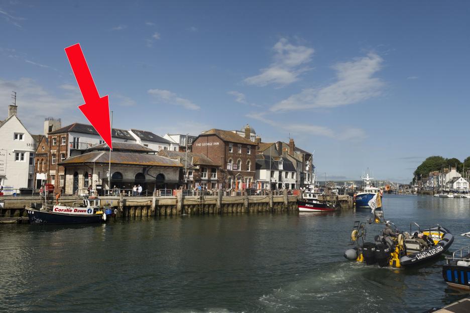 A red arrow pointing to the Old Fish Market at Weymouth Harbor.