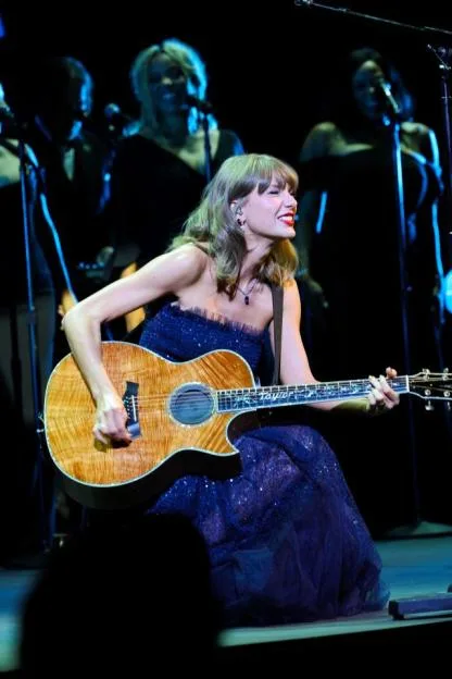 Taylor Swift performs onstage with an acoustic guitar during the Academy Museum Gala.