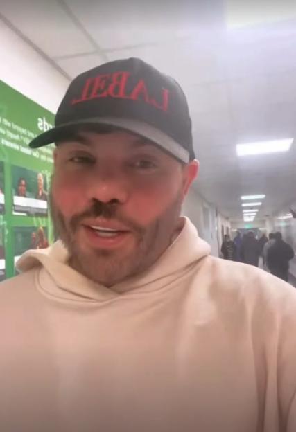 Bobby Norris wearing a black baseball cap and a cream hoodie in a hospital hallway.