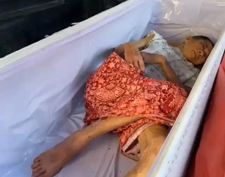 A 65-year-old Thai woman lying in a coffin, discovered alive.