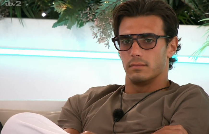 A man with dark hair, glasses, and a serious expression.