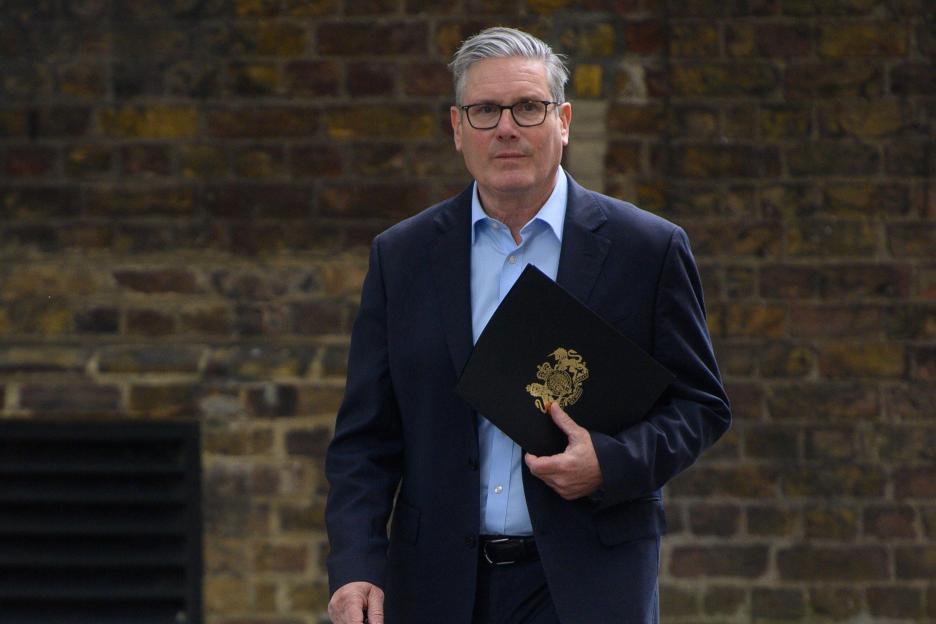 British Prime Minister Sir Keir Starmer in Downing Street, holding a folder with the Royal Coat of Arms.
