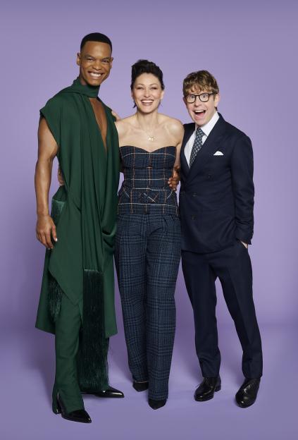 Johannes Radebe, Emma Willis, and Josh Widdicombe, the new hosts of Strictly Come Dancing, standing against a purple background.