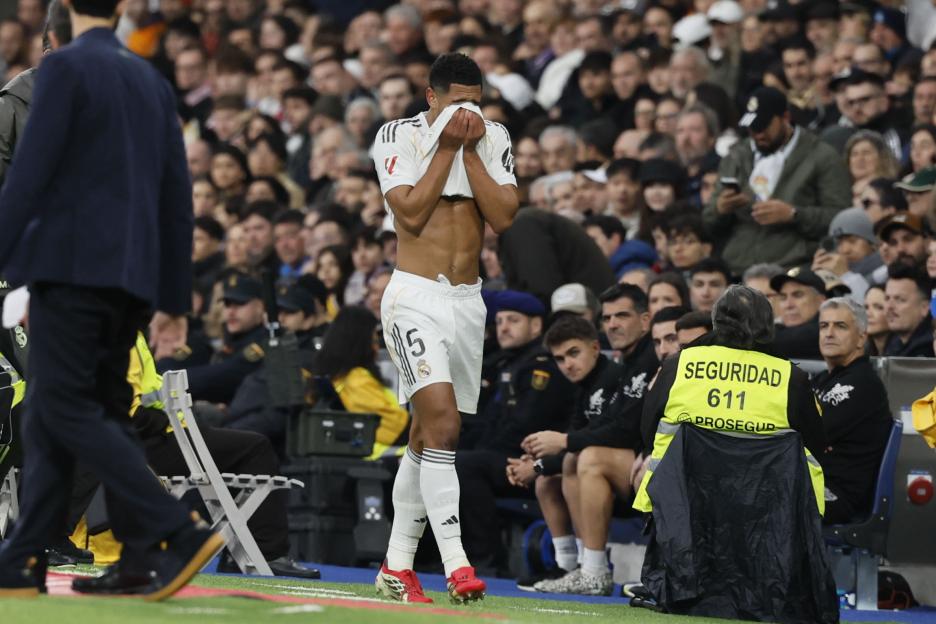 Jude Bellingham covers his face after being withdrawn from the match due to injury.