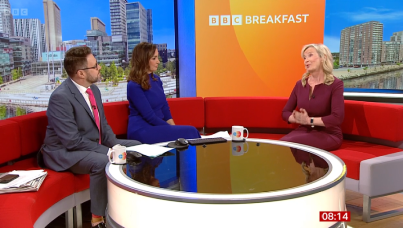 Three people on a red sofa in a TV studio, with "BBC BREAKFAST" on the screen behind them.