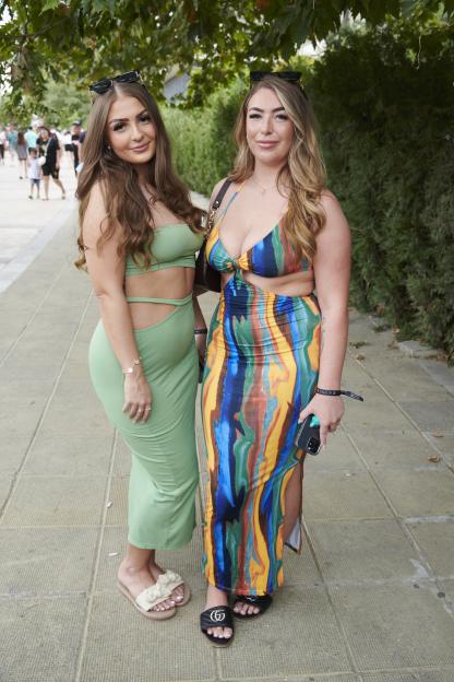 two women standing next to each other with one wearing a green dress
