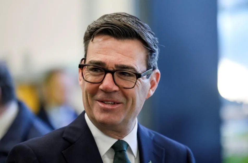Andy Burnham wearing glasses and a suit.