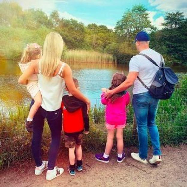 Paddy McGuinness and Christine with their three children looking at a lake.