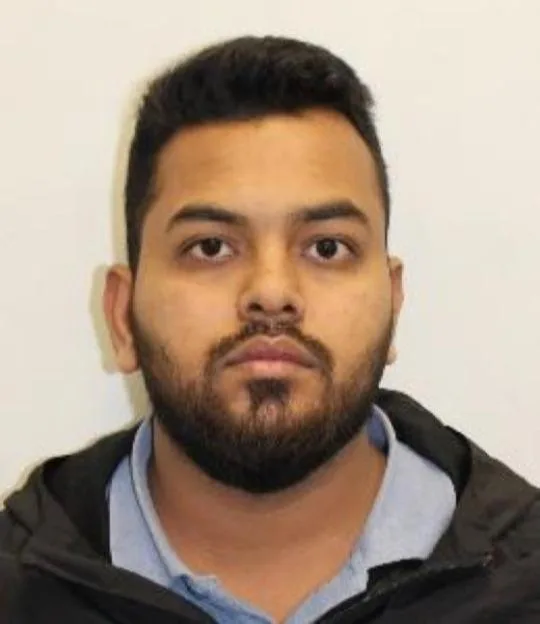 Headshot of a man with dark hair and a beard, wearing a light blue collared shirt and a dark jacket.