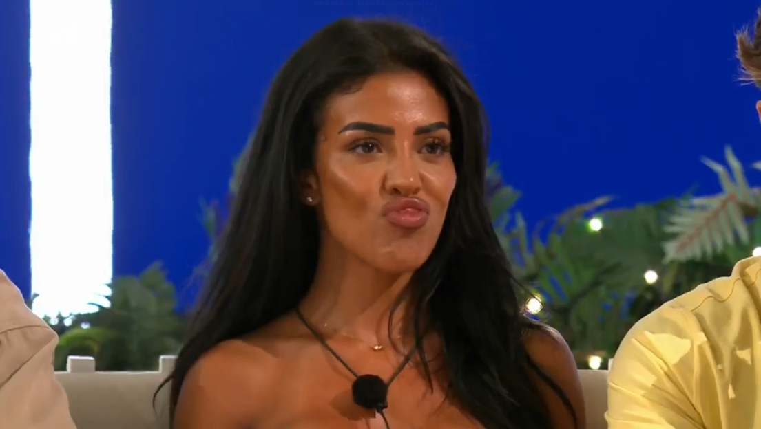 A woman with dark hair making a puckered lip expression.