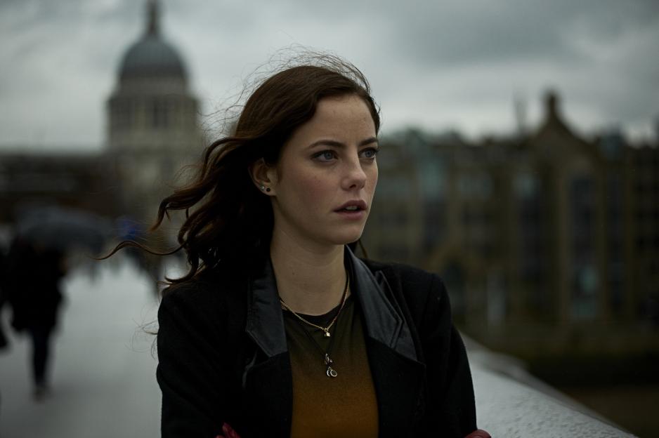 A woman, Kaya Scodelario as Effy Stonem in "Skins," looks right on a windy day, a dome building in the blurred background.