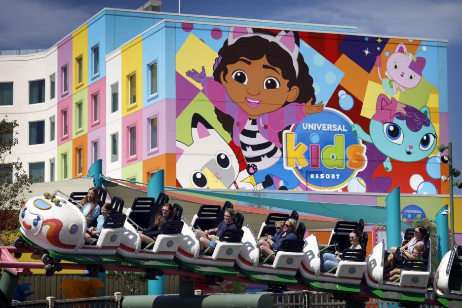 Families riding a rollercoaster in front of the colorful Universal Kids Resort.