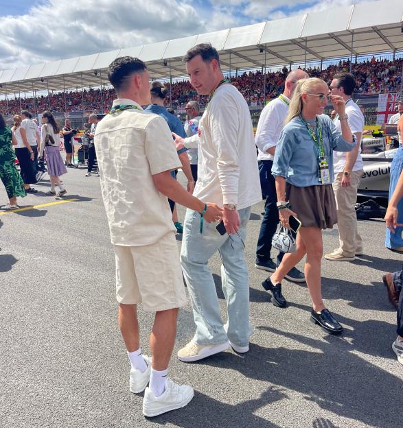 Two men talking on a track, with spectators in the background.