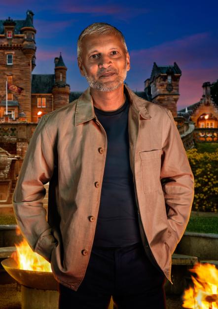 Maz, a 59-year-old civil servant from Preston, standing in front of a castle with a fire pit.