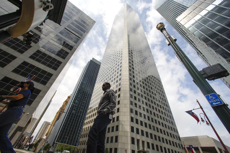The 75-story JPMorgan Chase Tower in Houston, Texas, seen from the street, with a man standing nearby.