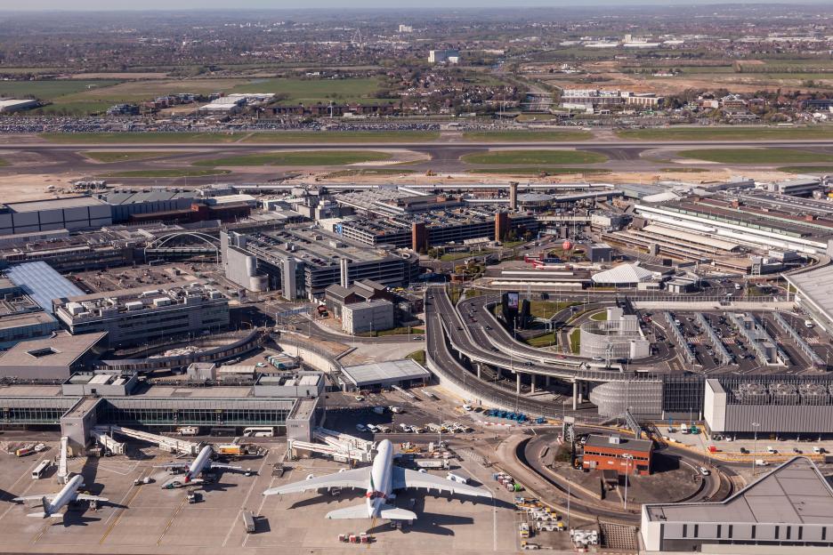 Aerial view of London Heathrow Airport with planes parked at the gates, runways, and buildings.