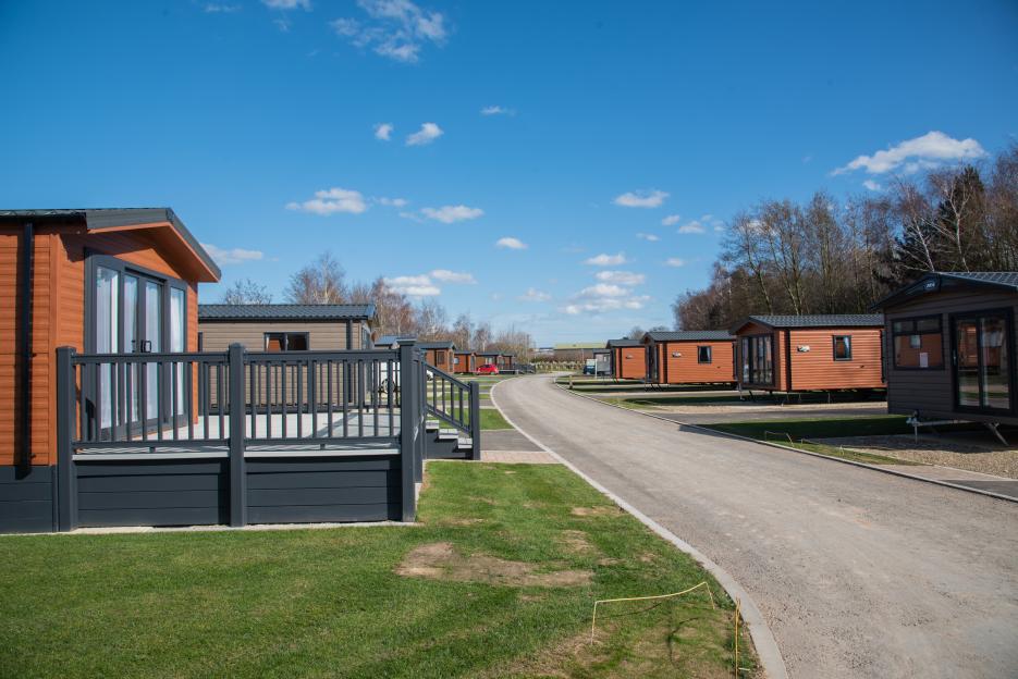 A view of a road with several mobile homes on either side of a road, with a blue sky overhead.