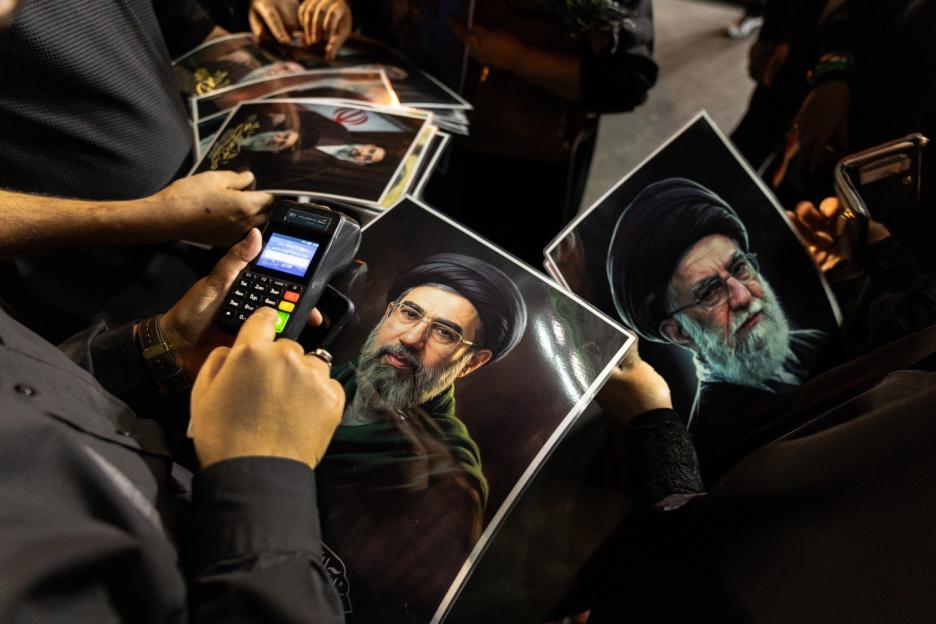 People purchasing posters of Supreme Leader Khamenei with a credit card machine.
