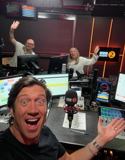 Vernon Kaye and his team waving in the BBC Radio 2 studio.