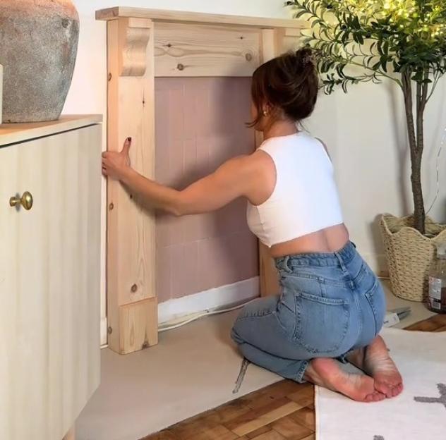 A woman installing a faux fireplace.
