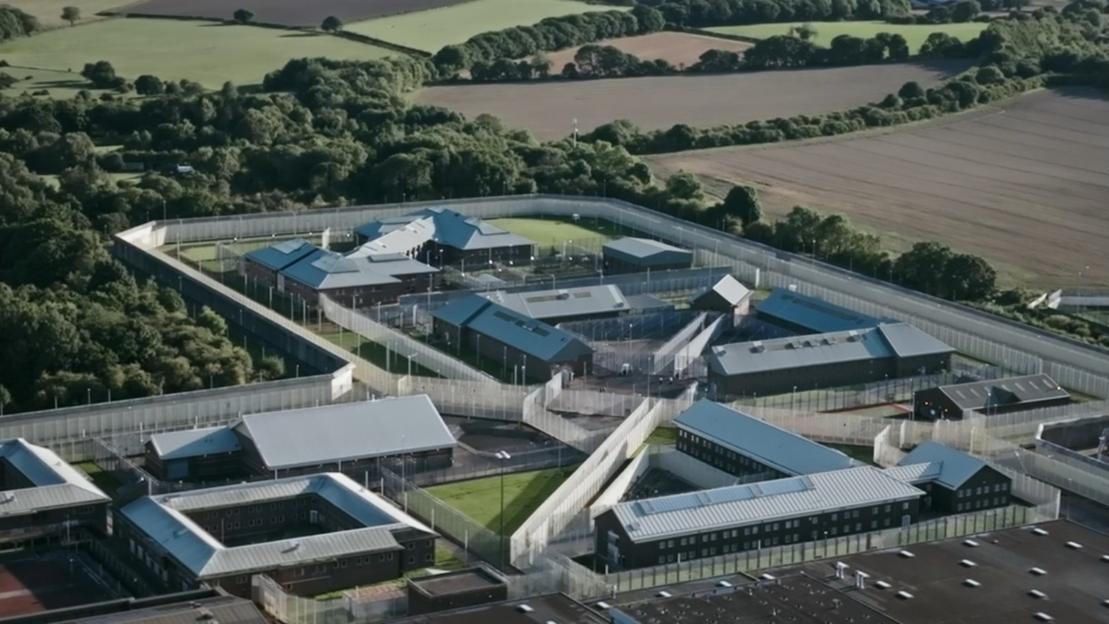 An aerial view of HMP Frankland prison, showing multiple buildings and high fences, surrounded by green fields and trees.