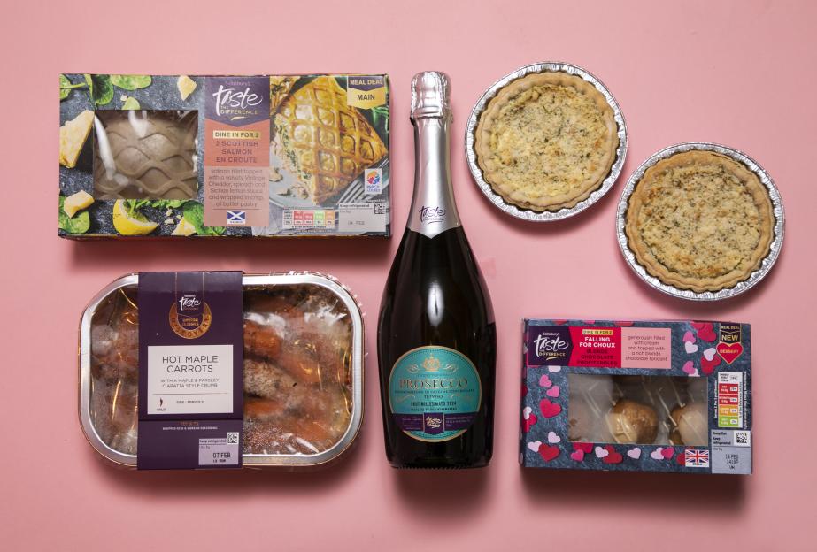 Four grocery items for Valentine's Day: a heart-shaped garlic bread, a bottle of Prosecco, heart-shaped lobster pasta, and mini pancakes.