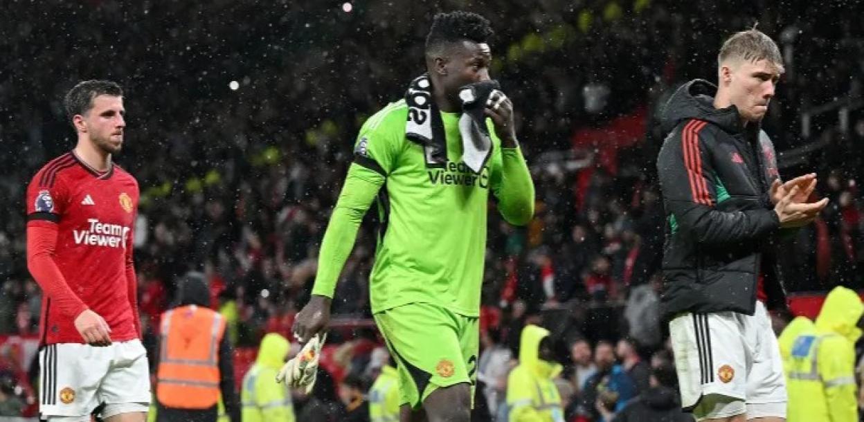Mason Mount, André Onana and Rasmus Højlund walk off the field during a rainy Manchester United v Manchester City match.