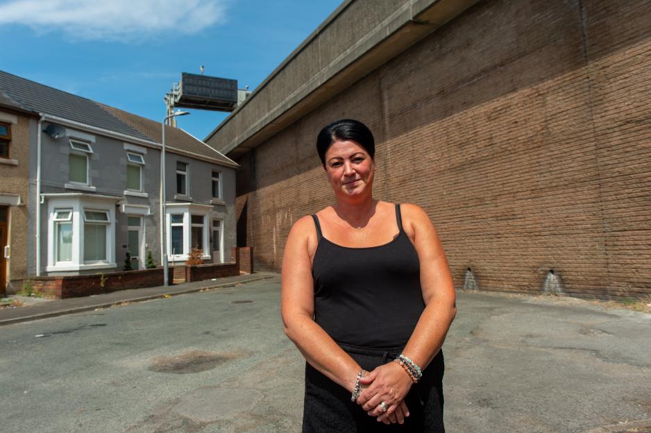 Claire Reeves stands in front of her home with an M4 motorway overpass behind her.