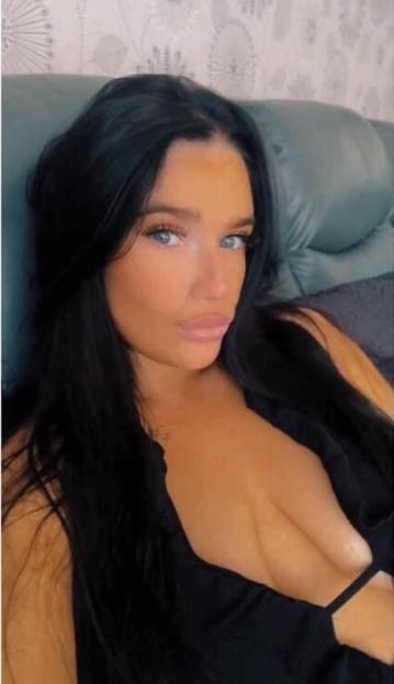 Amy McNamara, a woman with long dark hair and light eyes, wearing a black top.