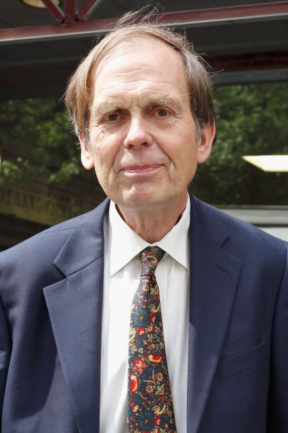 John Montagu, 11th Earl of Sandwich, smiling in a navy suit and patterned tie.