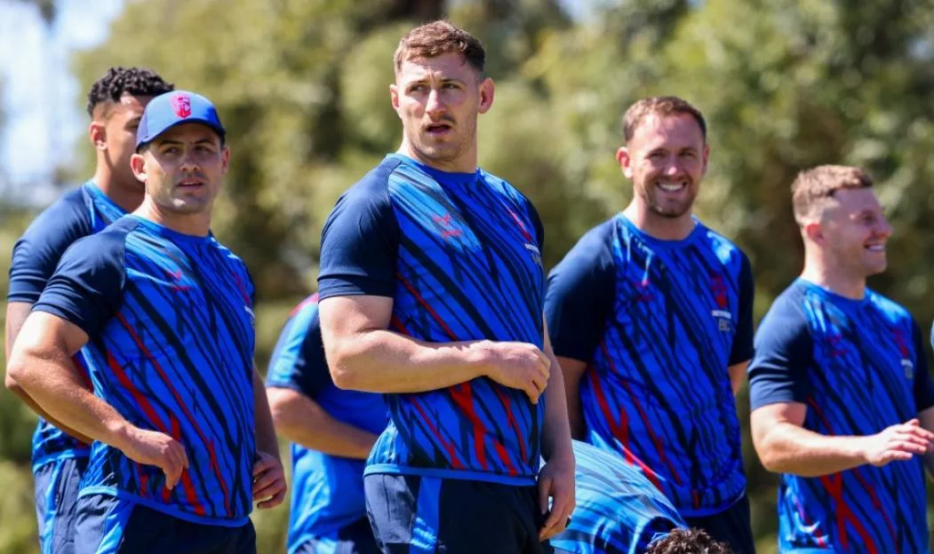 Rugby players in blue and black patterned training jerseys standing together outdoors.