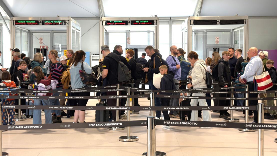 Crowds of passengers standing in a queue for security check at Faro Airport in Portugal.