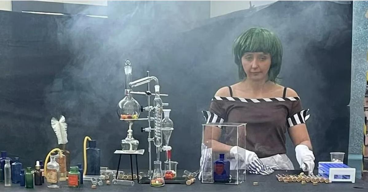 a woman in a green wig stands in front of a table full of bottles