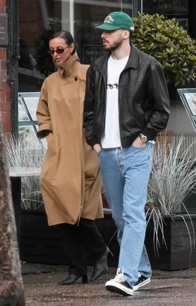 Maya Jama in a camel coat and Ruben Dias in a black leather jacket walk side-by-side.