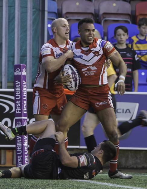Rugby players Mason Caton-Brown and teammate celebrating a try over an opposing player.