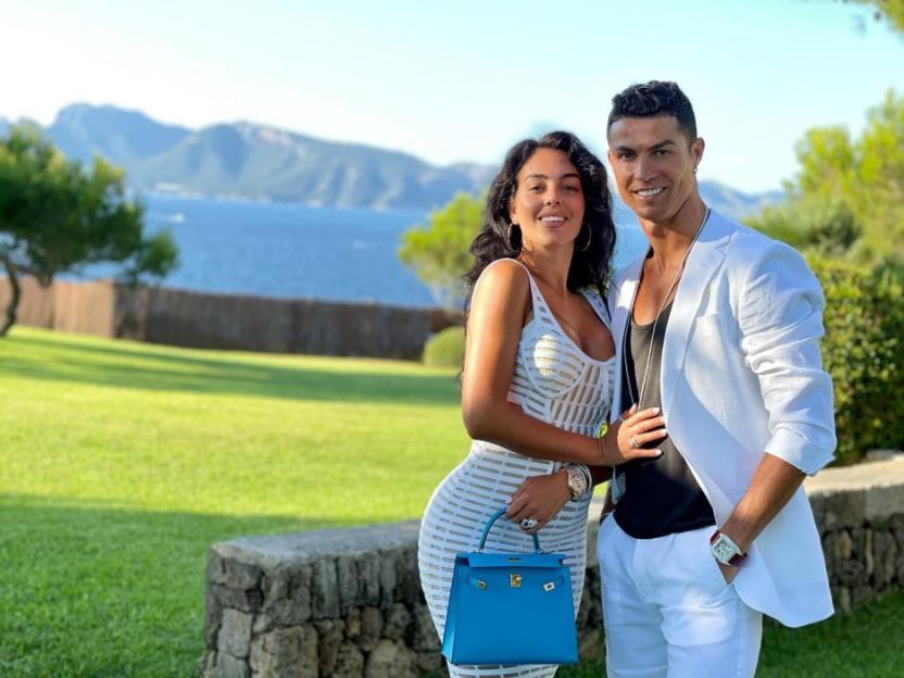 Cristiano Ronaldo and Georgina Rodríguez stand outdoors, smiling.