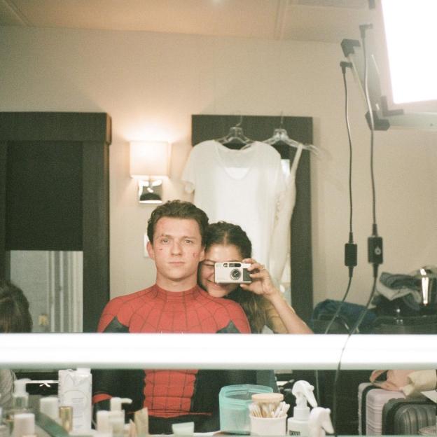 Tom Holland as Spider-Man and Zendaya taking a selfie in a mirror.