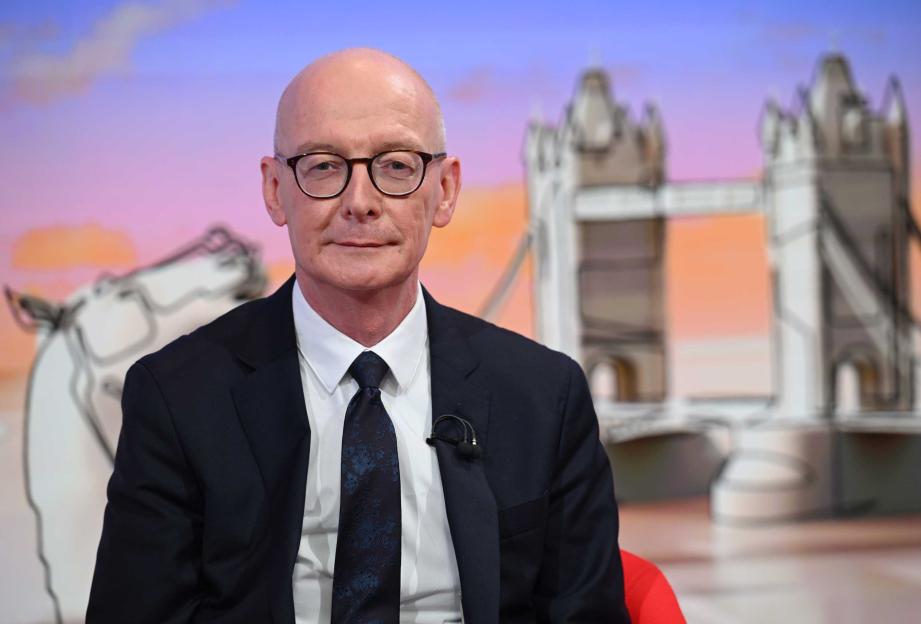 A male student resting his head on his arm on a desk full of school supplies.