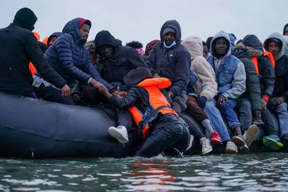 Migrants boarding a boat on the beach at Dunkirk, France.