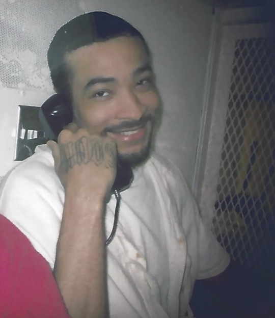 James Broadnax smiling while holding a phone receiver to his ear.