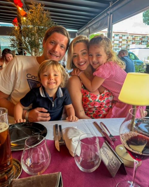 Family of four smiling at a restaurant table.
