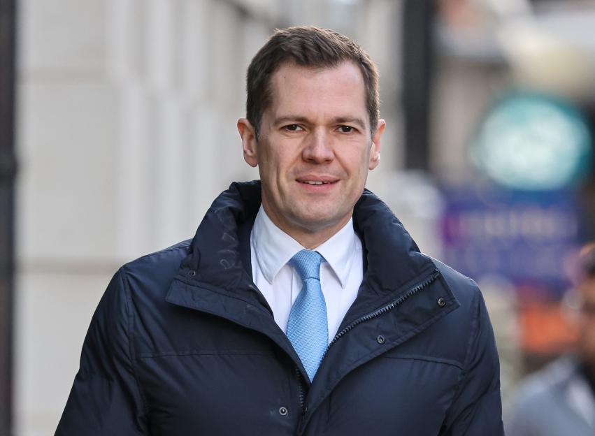 Robert Jenrick wearing a blue puffer jacket and a light blue tie.