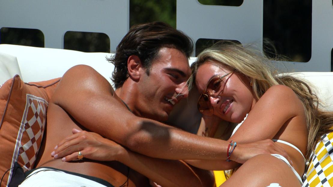 Lorenzo Alessi and Yasmin Hadlow embracing on a sofa during the TV show 'Love Island'.