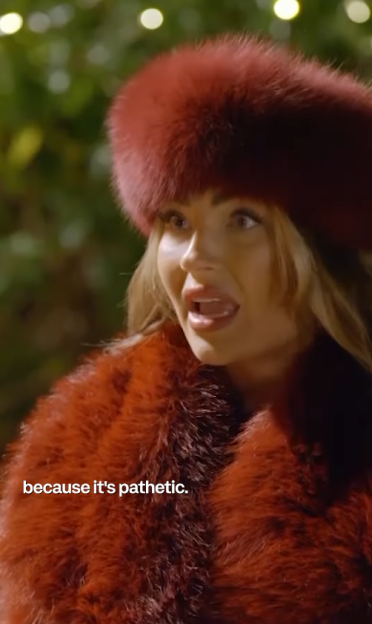 Woman in red fur hat and coat with her mouth open, stating "because it's pathetic."