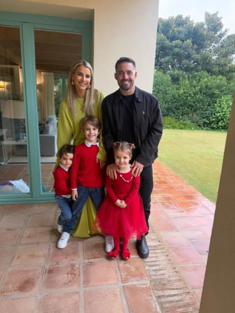Family of five posing together on a patio.