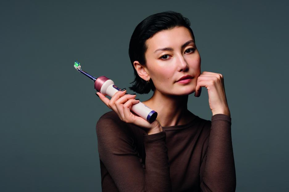 A woman holds a Dyson toothbrush.