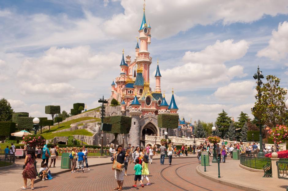Disneyland Paris castle with people walking on a sunny day.